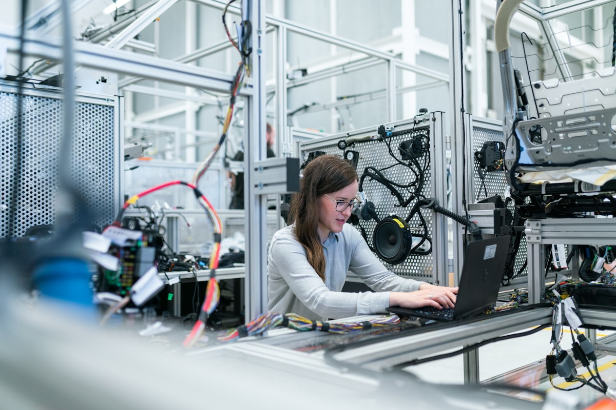 An engineer working at a laptop beside a production line